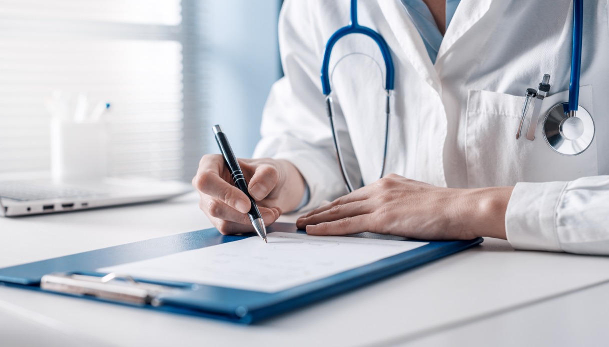 Doctor sitting at desk and writing a prescription for her patient